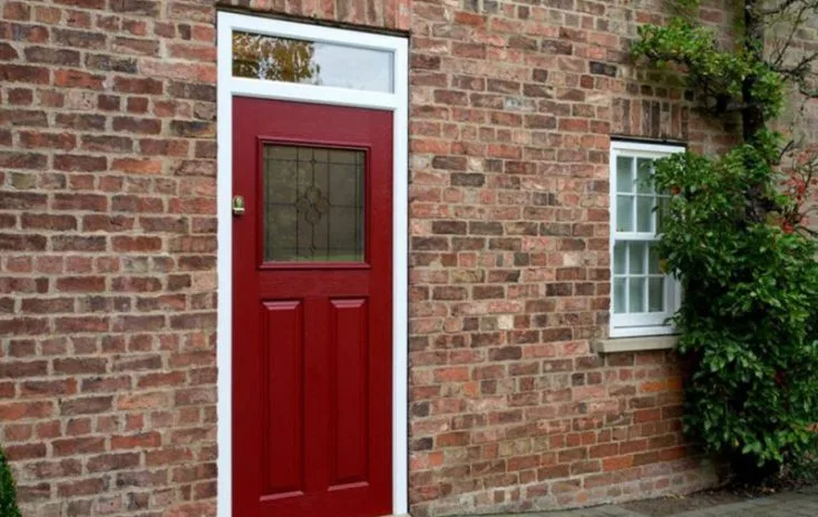Red composite door on traditional brick house